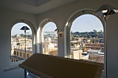 Floor lamps in a room with arched windows and a view of a Mediterranean city