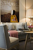 Gray upholstered sofa set with cushions in front of a wall with a picture and floor lamp