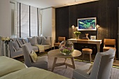 Table lamps in front of a living room wall with dark wood paneling with a TV and light gray sofa