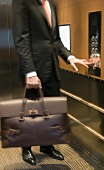 Person with a briefcase pushing the buttons in an elevator