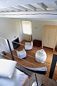 View from a mezzanine into a living room with armchairs and white bean bag chair on a tiled floor