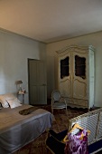 Half-darkened bedroom of a country home with period furniture and a double bed