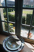 Stacked bowls on a window sill, behind it a view of a garden