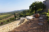 Terrace with a table and chairs on terracotta flooring with a view of the Mediterranean countryside