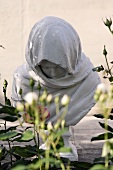 Bust of the Virgin Mary on a stone base in a garden