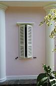 Fenster mit weissen Holzläden und rosafarbener Hausfassade mit Halbsäulen