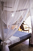 Elegant canopy bed with tied back, sheer curtains