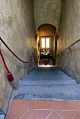 Looking down a flight of steep stairs in a house with a view of a pedestal and a window