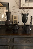 Black handcrafted metal containers on a vintage style wooden chest of drawers