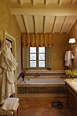 Vor Fenster eingebaute Badewanne mit gemusterten Fliesen und Holzdecke im Dachraum