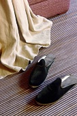 Black slippers on a blue and white striped carpet