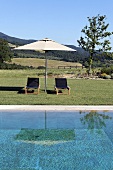 Entspannung am Pool mit Liegestühlen unter Sonnenschirm, und Blick auf Mediterraner Landschaft