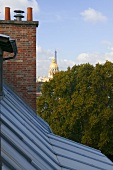 View across a roof and a brick chimney of a gold plated church dome