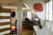 Converted attic with white column and view of a leather couch in a open living room