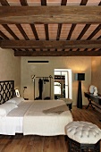 An elegant bedroom beneath a rustic wooden beam ceiling in a renovated country home