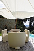 White plastic patio furniture on a wooden terrace under an awning