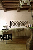 Renoviertes Landhaus mit rustikaler Holzbalkendecke-Hocker im Asienstil und Bett mit Kopfteil aus schwarzem Metallgitter