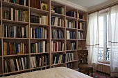 Pink bookshelves in a bedroom and lightweight curtains at the window