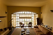 Yellow living room in a country home with furniture upholstered in light fabric and floor to ceiling arched lattice windows