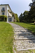 Gravel path through a garden and an elegant villa