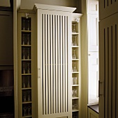 Light colored kitchen cupboard with slits in the front and built in shelves with glass