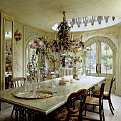 A dining room in a Baroque castle - a crystal chandelier hanging above a marble-topped table with metal legs and arched doors leading onto a terrace
