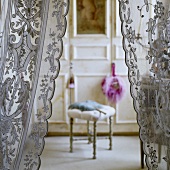 A view through a light lace curtain onto a stool