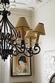 A chandelier with beaded ornaments and yellowed lamp shades