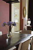 Flowers in a glass vase on a wooden dining table and a dark red wall