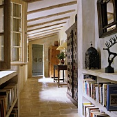 A terracotta floor in the hallway of a country house with a concrete shelf and a rustic wood beamed ceiling