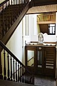 Treppenhaus mit dunkler Holztreppe und Geländer mit Blick auf rustikalem Spiegelschrank
