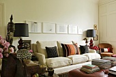 Table lamps with black shades next to a light-coloured upholstered sofa with cushions on it