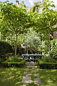 Sonniger Tag im Garten mit Hecke um Baum und idyllischer Terrassenplatz