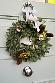 A Christmas wreath on a white front door with pine sprigs and animal figurines
