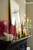 Pink vases and burning candles on a black mantelpiece