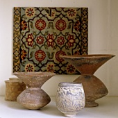 Antique folk art style stone containers in front of a picture with an oriental design
