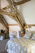 A queen-sized bed and a chandelier in a rustic attic room in a country house