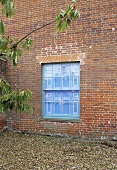 A gravel path in front of a house with a brick facade and a window