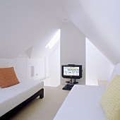 Attic room (minimalist design) with single beds under a pitched roof and a TV