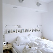 Bett mit weisser Bettwäsche und Bildergalerie in Wandnische und schwenkbaren Tischleuchten