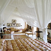 A white canopy above a bed and elegant chairs and rugs in a bedroom