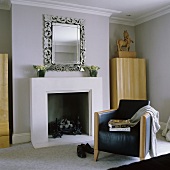 A black leather armchair in front of a fireplace with a silver-framed mirror above it
