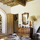 Living room in a Provencal style country home with rustic wooden ceiling and sideboard next to a wide open door