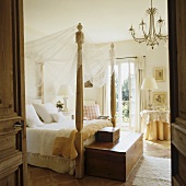 Four poster bed with canopy and hope chest at the foot of the bed in a Mediterranean bedroom