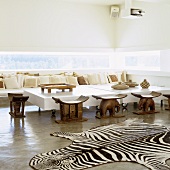 A Mediterranean designer house - a zebra rug in front of ethnic wooden stools and a designer coffee table