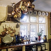 Copper pots hanging from a wooden ceiling beam in the kitchen of a country house