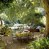 A view of a table covered with a cloth and chairs in a garden