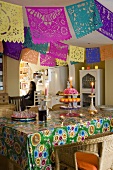 Christmas decorations made of colourful paper and a candlestick on a table spread with a colourful tablecloth