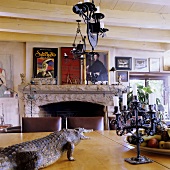 A dining room with wood beam ceiling in a South African country house - a stuffed crocodile and a chandelier hanging above a table