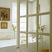 An open bathroom door with a view of a white bathtub and pictures in gold frames hanging on the wall